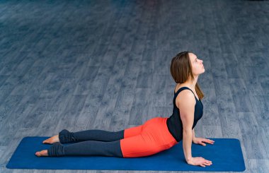Sportif kadın yoga yapıyor, spor merkezinde mavi minderin üzerinde egzersiz yapıyor. Yoga stüdyosunda ellere dayalı pozisyon duruş yatan rahat spor güzel ince kadın.
