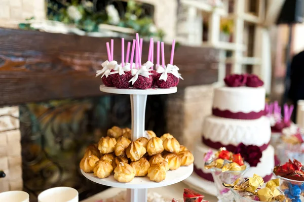 Stylish candy bar with cakes, candies, sweet cookies, cake pops. Delicious assortment for wedding banquet. Candy bar inside the restaurant.