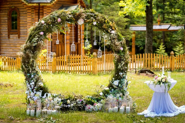 Arch for the wedding ceremony. Decorated with fabric flowers and greenery. Is located in a pine forest. Background church. Wedding decorations in rustic style. Just married. Wedding decor.