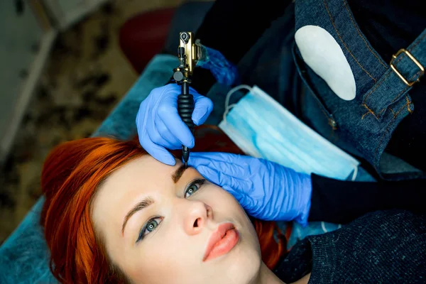 Professionele schoonheidsspecialist wenkbrauw tattoo vrouw gezicht doen. Permanente wenkbrauw make-up in de schoonheidssalon. Cosmetologie behandeling. — Stockfoto