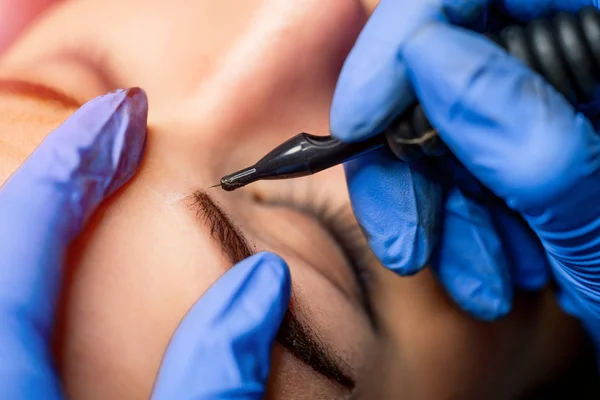 Visagist werken, waardoor permanente make-up in de schoonheidssalon. Schoonheidsspecialiste maken van permanente make-up voor wenkbrauwen. — Stockfoto