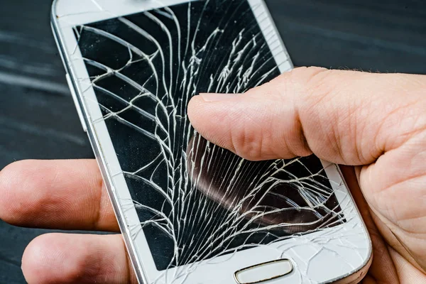 Broken phone screen in hand. Broken glass of smartphone