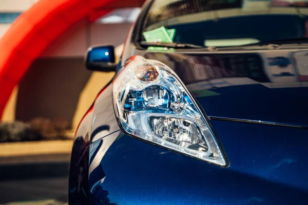 Electric car headlight. Hybrid car - new model car presentation in showroom