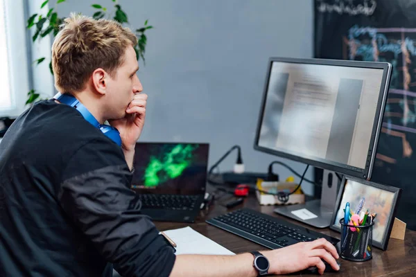 Sérieux jeune homme concentré sur le problème sur l'écran du PC. Programmeur intelligent travaille dur dans son entreprise à l'intérieur . — Photo