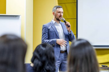 İdari lider halka açık seminerde mikrofona konuşuyor. Konferans sırasında seyirciye profesyonel konuşmacı öğretiyor.