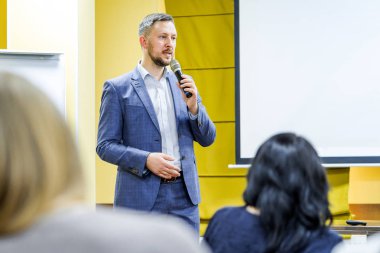 İdari lider halka açık seminerde mikrofona konuşuyor. Konferans sırasında seyirciye profesyonel konuşmacı öğretiyor.