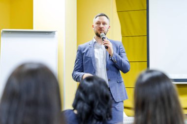 İdari lider halka açık seminerde mikrofona konuşuyor. Konferans sırasında seyirciye profesyonel konuşmacı öğretiyor.