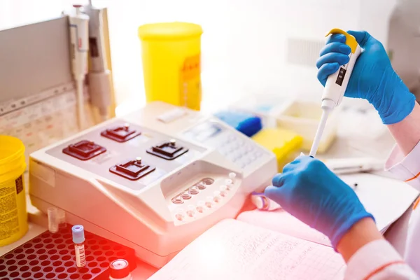 Trabajadores de laboratorio profesionales vertiendo muestras de sangre en viales sobre la mesa. Técnicos de laboratorio médico haciendo experimentos de sangre en clínica de investigación . — Foto de Stock