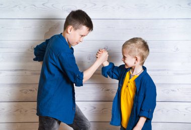 Stüdyoda oyun sırasında mutlu ve samimi kardeşler. Ahşap duvar arka planında izole edilmiş elleriyle savaşan iki pozitif arkadaş. Duygu ve enerji ile mutlu çocukluk.