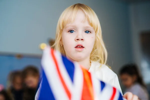 Klein meisje speelt met Britse vlag. Glimlachend meisje houdt de Britse nationale vlag als een teken van patriottisme. — Stockfoto