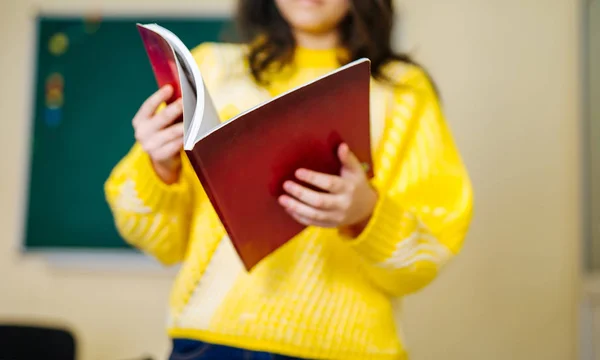 Portrait of cute girl reading book in classroom. Educational process. — Stock Photo, Image