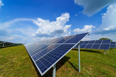 Mavi gökyüzü arka plan üzerinde güneş paneli. Yeşil çimenler ve bulutlu gökyüzü. Alternatif güneş enerjisi konsepti