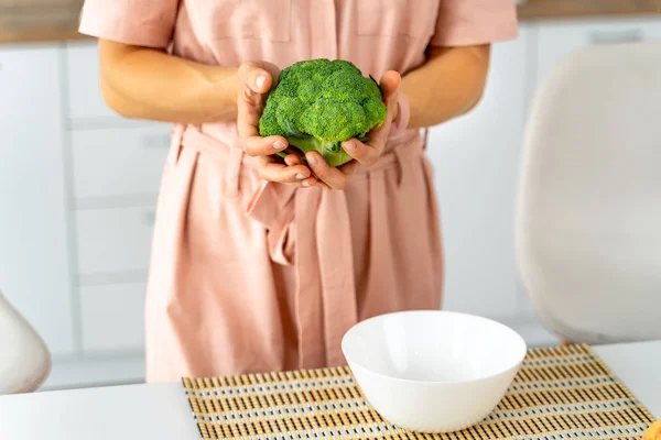Ung lycklig kvinna som innehar broccoli i det vackra köket. Hälsosam mat och bantning koncept. Förlora vikt — Stockfoto