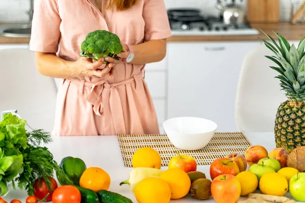 Jovem mulher feliz segurando brócolis na bela cozinha. Alimentação saudável e conceito de dieta. Perder peso — Fotografia de Stock