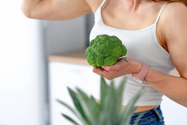 Mulher forte com brócolis na cozinha. Nutrição saudável — Fotografia de Stock