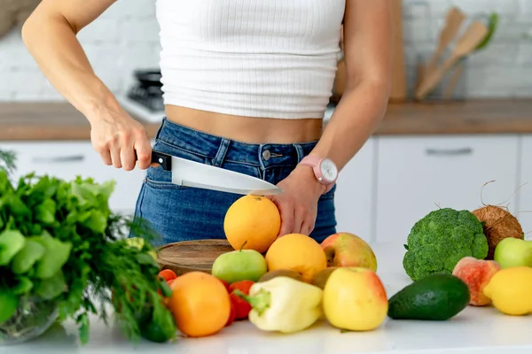 Menina bonita jovem corta laranja fresca para preparar suco fresco na cozinha. Dieta de desintoxicação . — Fotografia de Stock