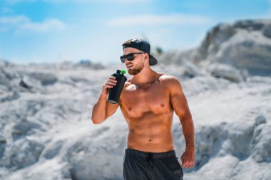 Profesyonel vücut geliştirmeci içme. Spor kavramı açık havada.