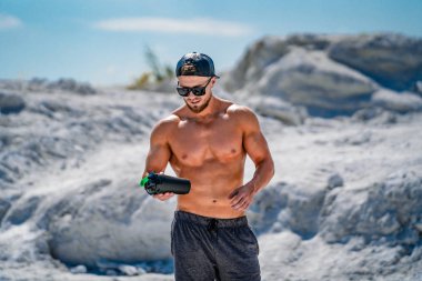 Mükemmel, omuzlar, pazı, triceps ve göğüs mavi gökyüzü arka planda açık havada poz ile Bodybuilder. Güçlü, atletik bir adam çıplak gövdeyle ayakta duruyor. Güzel sağlıklı vücut kavramı.