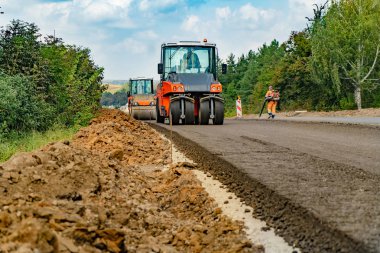 Yeni yol inşaatında çalışan yol silindirlerinin yakın görüntüsü. Yol kaldırımı
