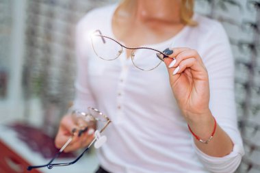 Genç bir kadın gözlükçüden gözlük seçiyor..