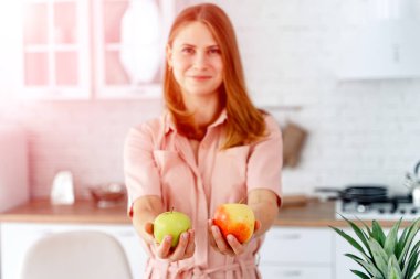 Mutfakta sebze ve meyvelerle yemek hazırlamaya hazır bir kadın var. Kadının elinde elmalar var. Mutfak geçmişi. Sağlıklı yiyecekler. Vejetaryen. Vejetaryen..
