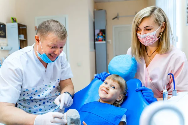 Mała dziewczynka w gabinecie dentystycznym. Zespół dentystów pracuje. Stomatologia. — Zdjęcie stockowe