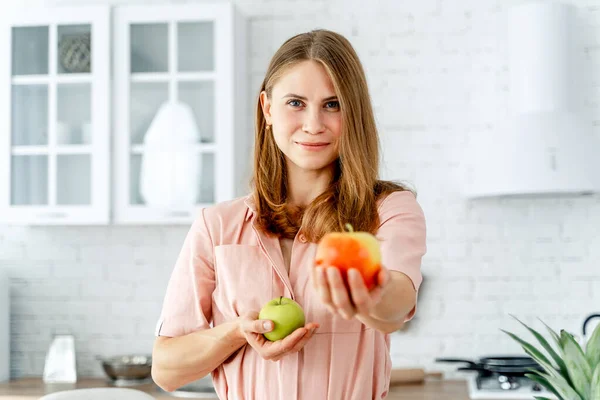 Γυναίκα στην κουζίνα έτοιμη να προετοιμάσει το γεύμα με λαχανικά και φρούτα. Γυναίκα κρατά μήλα.Φόντο κουζίνας. Υγιεινή τροφή. Χορτοφάγοι. Βοτανοειδή. — Φωτογραφία Αρχείου