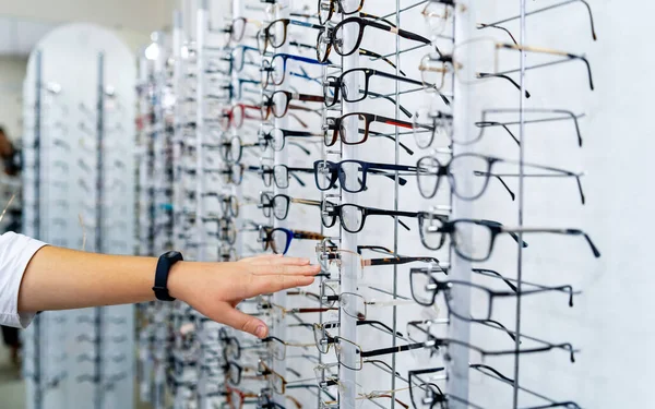 Fila de gafas en una óptica. Tienda de anteojos. Ponte de pie con gafas . — Foto de Stock