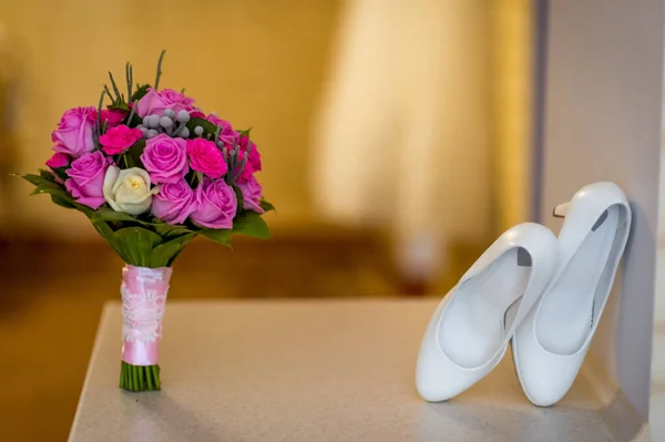 Wedding white shoes and bouquet of pink and purple roses. Bridal photosession. Closeup. — Stock Photo, Image