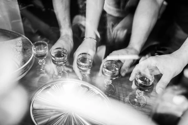 Black and white photo of people holding glasses of alcohol. Feast, spirits. Celebration. B-Day. Wedding day.