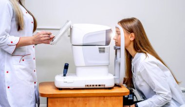 Genç kadın göz testi yapıyor. Görme düzeltmesi. Optalmolory 'deki sarışın kız. Optik kliniği. Bir müşterisi olan bir oftalmolog. Klinik geçmişi. Oftalmolojik ekipmanlar. Yakın çekim..