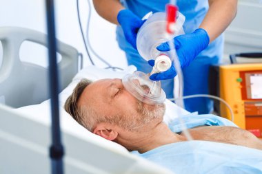 Doktorlar hastaya hastanede oksijen maskesi takıyor. İlk yardım. Reanimasyon odası. Tutarsız hasta.