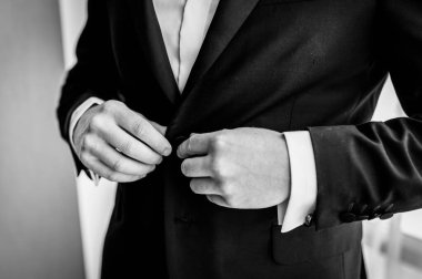 Damat 'ın düğün hazırlıkları. Damat ceketi ilikliyor. Düğün siyah beyaz fotoğraf konsepti. Yakın çekim..