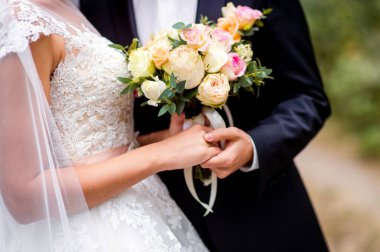 Düğün gününde gelin ve damat dışarıda yürüyor. Gelin çifti, mutlu yeni evli kadın ve erkek konsepti. Düğünü bir buketle yakından sevmek.