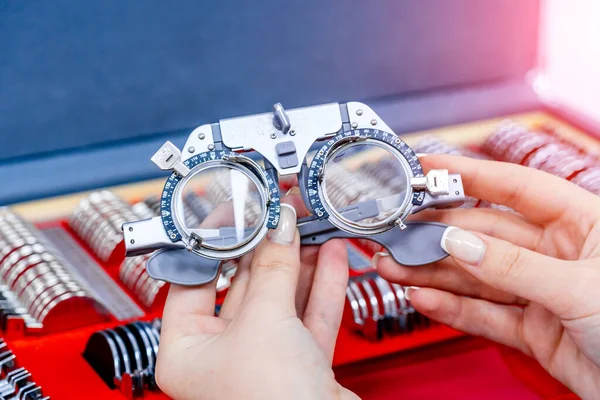 Close-up of ophthalmological trial frame and test glasses in woman's hands. Eysight correction. Young girl is holding corrective spectacles. — Stock Photo, Image