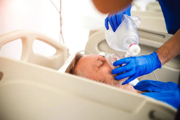 Ärzte setzen Patienten im Krankenhaus eine Sauerstoffmaske auf. Erste Hilfe. Reanimationsraum. Uneinsichtiger Patient. — Stockfoto