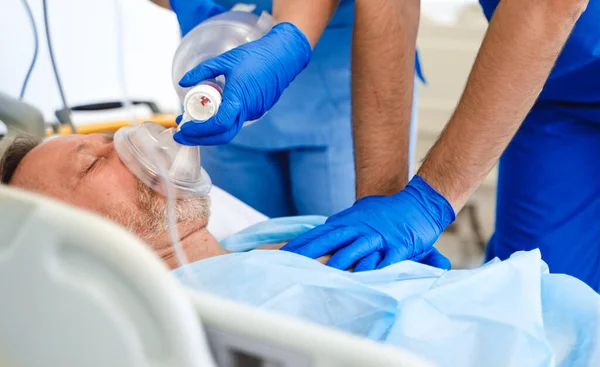 Ärzte setzen Patienten im Krankenhaus eine Sauerstoffmaske auf. Erste Hilfe. Reanimationsraum. Uneinsichtiger Patient. — Stockfoto