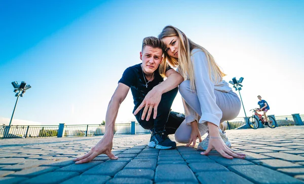 Jong stel poseert op een rotsweg. Samen zitten. Meisje en jongen hurken samen. Een film. Mooi meisje en een jongen. Mensen emoties. Kijken in de camera. — Stockfoto