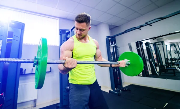 Sport, Bodybuilding, Lifestyle- und People-Konzept - junger Mann mit Langhantel lässt Muskeln spielen und Schulterpresse im Fitnessstudio in die Hocke gehen. — Stockfoto