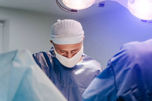 A műtét folyamata orvosi felszereléssel. Sebész a műtőben, sebészeti felszereléssel. Orvosi háttér. Orvos közelsége orvosi maszkban. — Stock Fotó