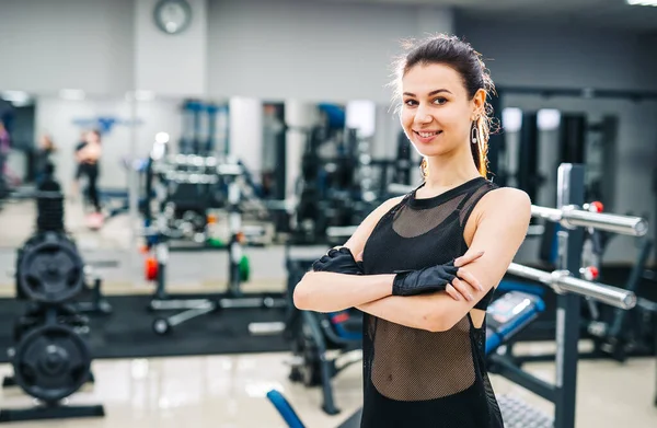 Jovem e bela desportista com bom corpo. Menina fitness morena com as mãos cruzadas. Antecedentes. Manchete preta. Fundo desfocado . — Fotografia de Stock