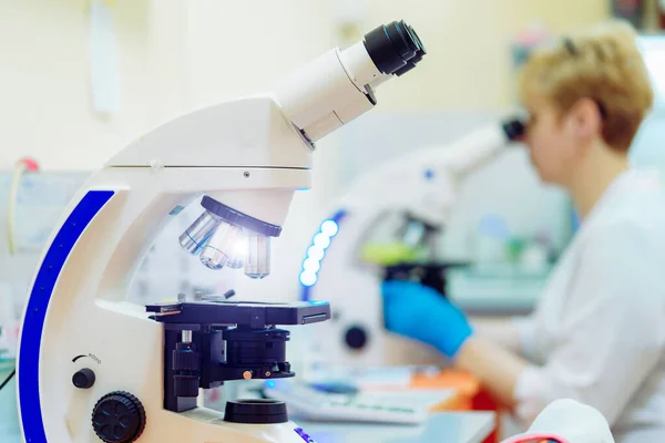 Científica con experiencia está trabajando en laboratorio e investigando con microscopio. Antecedentes de laboratorio químico moderno. Vista lateral . — Foto de Stock