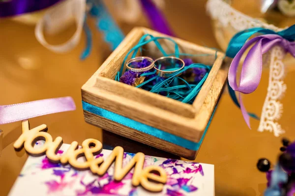Wedding Decoration. Golden rings in wooden box with colorful ribbons inside. — Stock Photo, Image