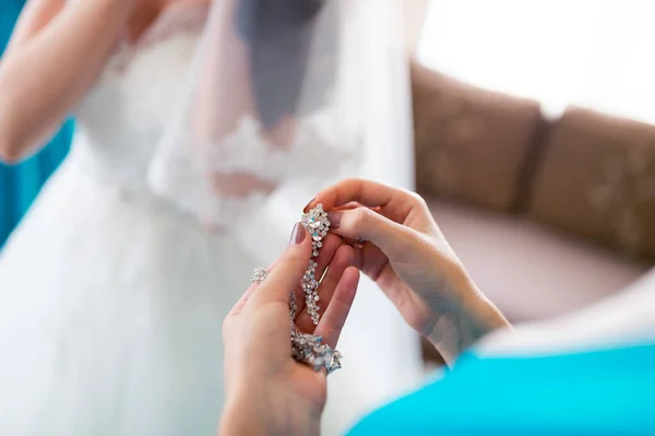 Gioielli pendenti in argento e un diamante ovale orecchini da donna per la sposa. Primo piano. Sposa sullo sfondo sfocato . — Foto Stock