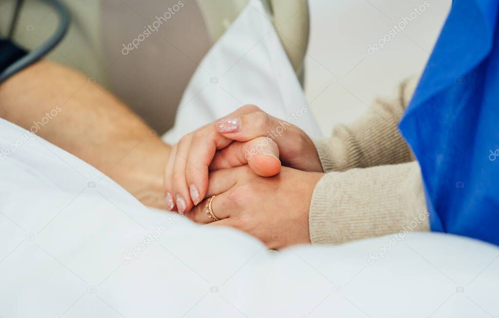 Holding patient hands in a hospital. Family help. Closeup. Support.