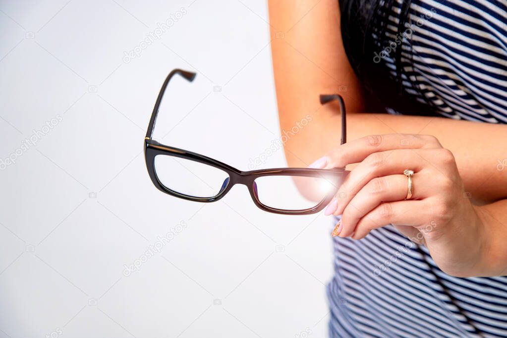 Spectacles closeup. Woman hand holds black framed eyeglasses.
