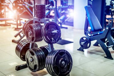 Spor salonundaki bir dambıl için kocaman krepler. Spor ve sağlıklı yaşam konsepti. Beden eğitimi arka planında krep seti. Spor ekipmanları yakın plan..