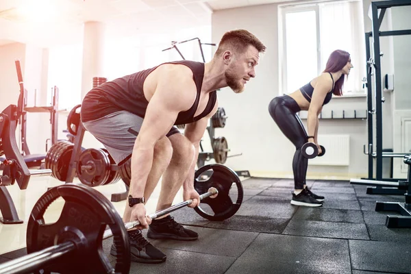 Spor, vücut geliştirme, yaşam tarzı ve insanların konsepti. Halter esneten ve spor salonunda omuz presi yapan genç erkek ve kadın. - Yakın çekim. Sağlıklı yaşam konsepti. — Stok fotoğraf