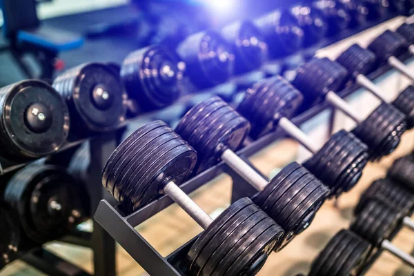 Hantelreihen in der Turnhalle mit verschwommenem Hintergrund. Nahaufnahme. Sportgeräte. Konzept für gesundes Leben. — Stockfoto