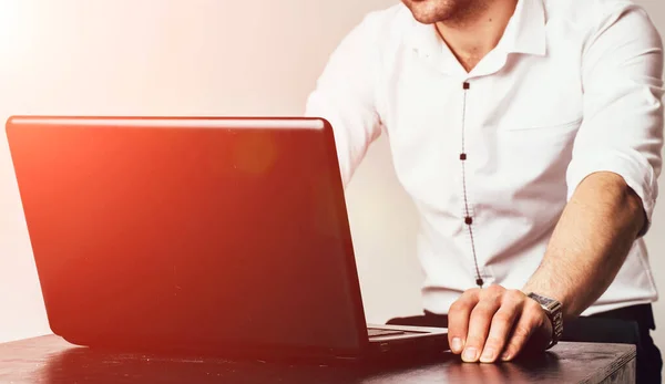 Cropped image of a young man working on his laptop at the table. Rear view of business man hands busy using laptop at office desk, young male typing on computer. Selective focus. Closeup. — Stockfoto